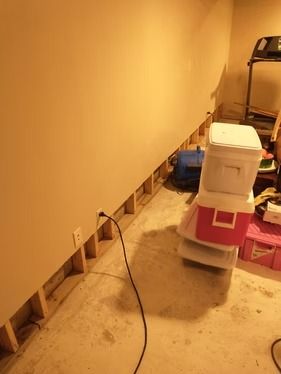 A partially removed wall exposing wooden studs in a basement.