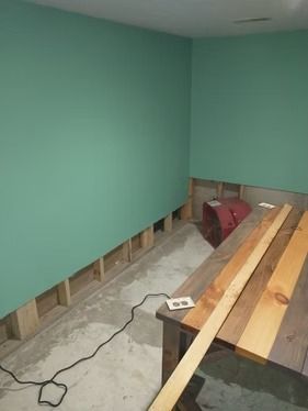 A corner of a room with green painted walls and an exposed wooden wall frame.