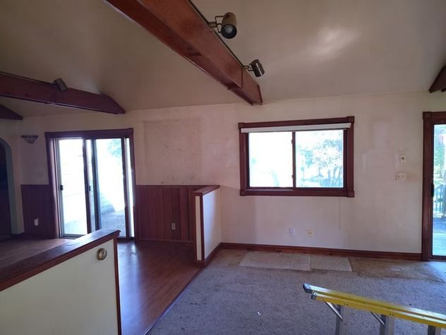 A room with light walls, wood trim, and beamed ceilings.