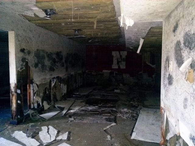 A dark, abandoned room with decaying, mold-spotted walls.