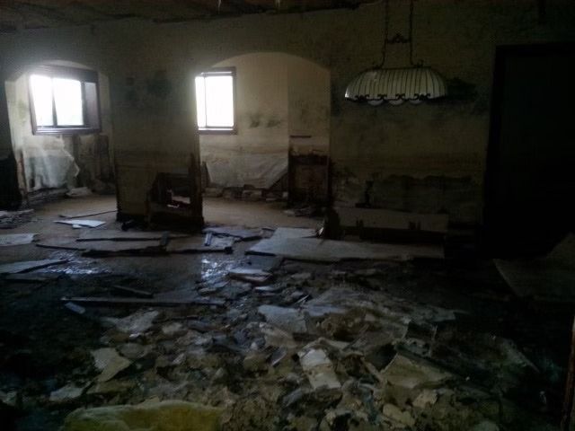 A dimly lit, dilapidated room filled with floor debris.
