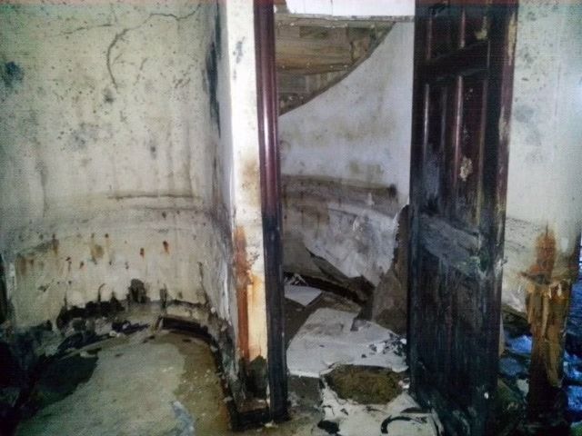 A dilapidated interior corner with peeling, stained walls.