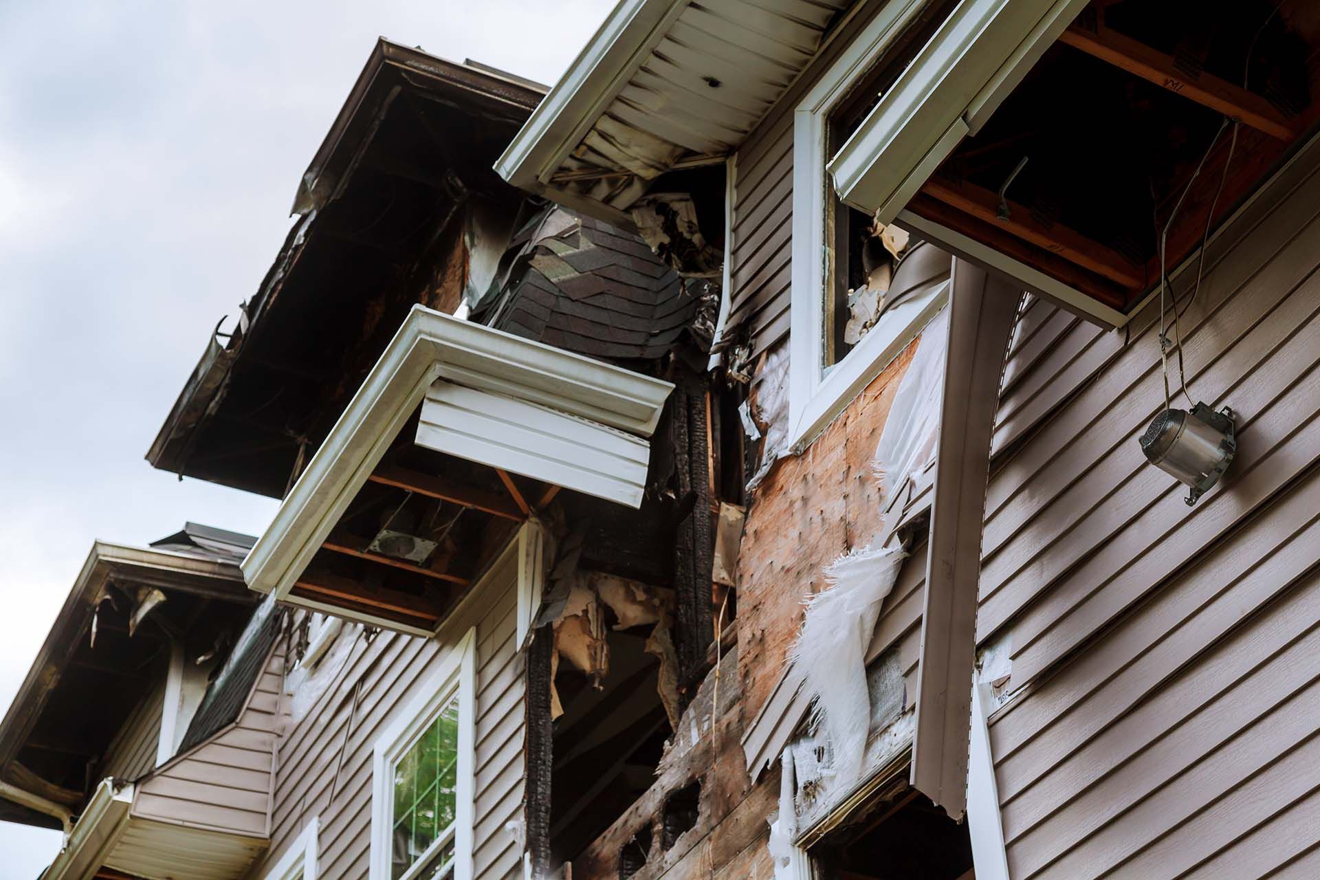 A low-angle view of a house exterior with significant fire damage.