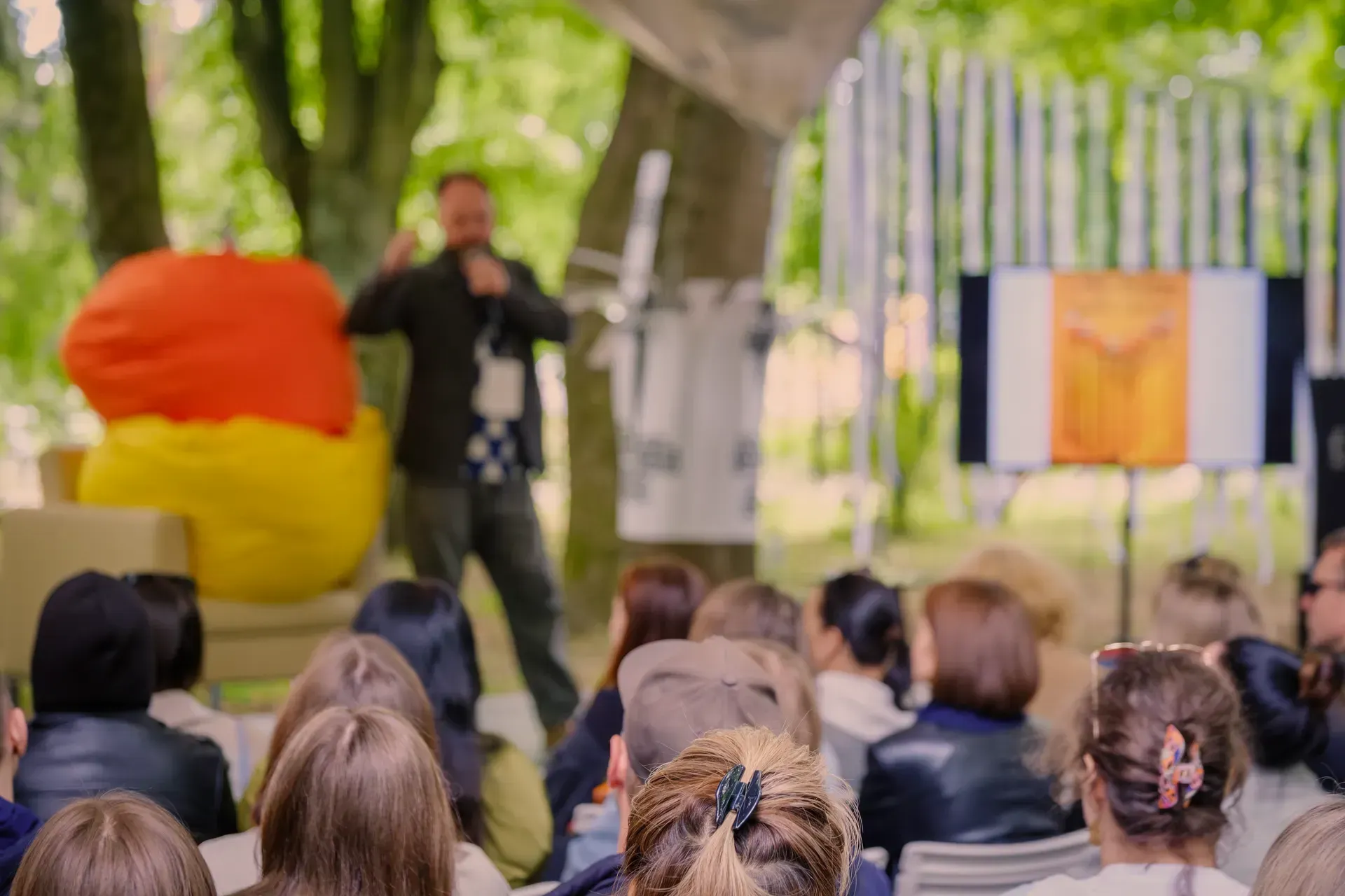 A man is giving a presentation to a group of people in a park.