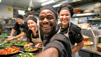 A group of chefs are taking a selfie in a kitchen.