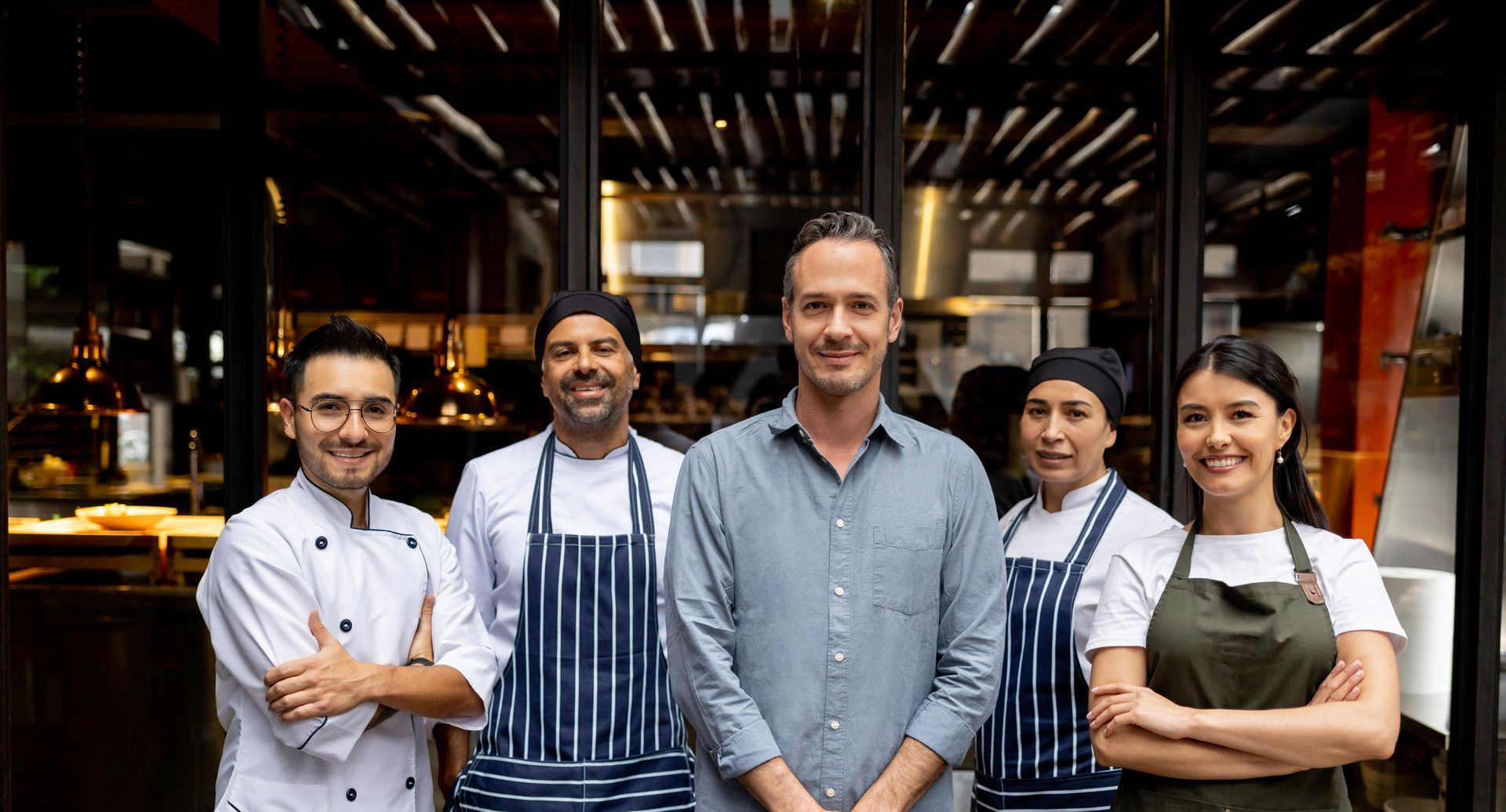 A group of chefs are posing for a picture in front of a restaurant.