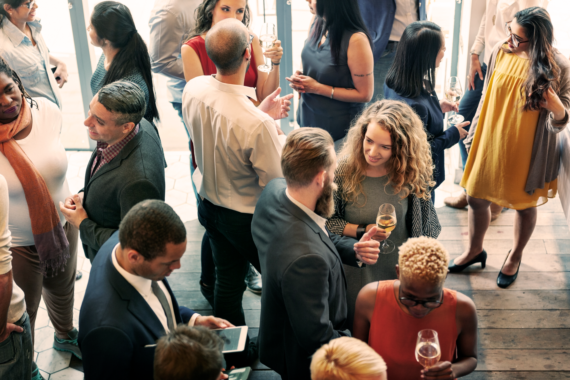 A group of people are standing in a room talking to each other.