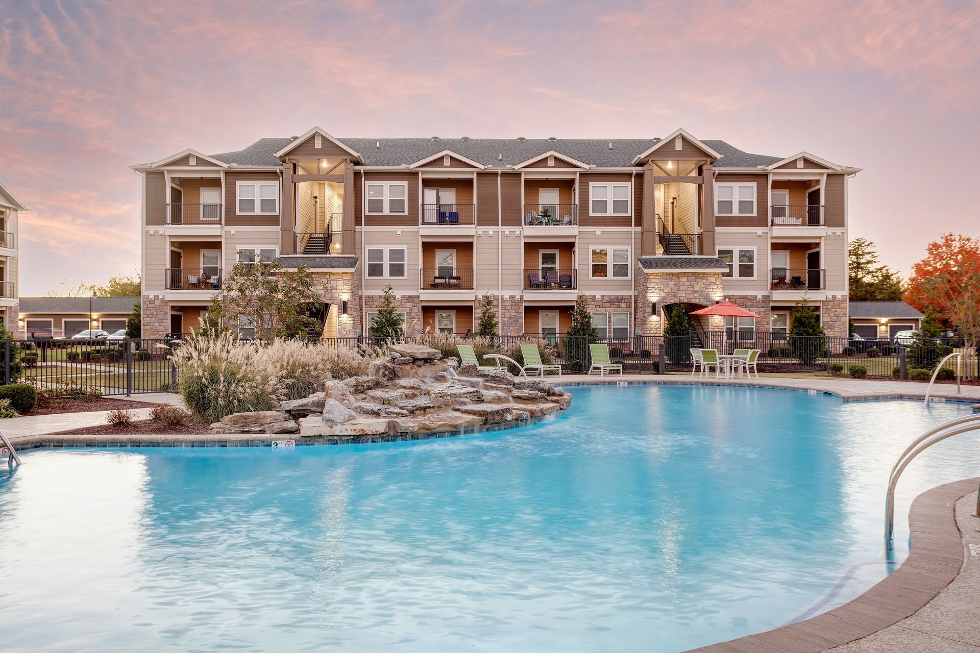 Large open room with hardwood floors, multiple seating areas, and a bar.