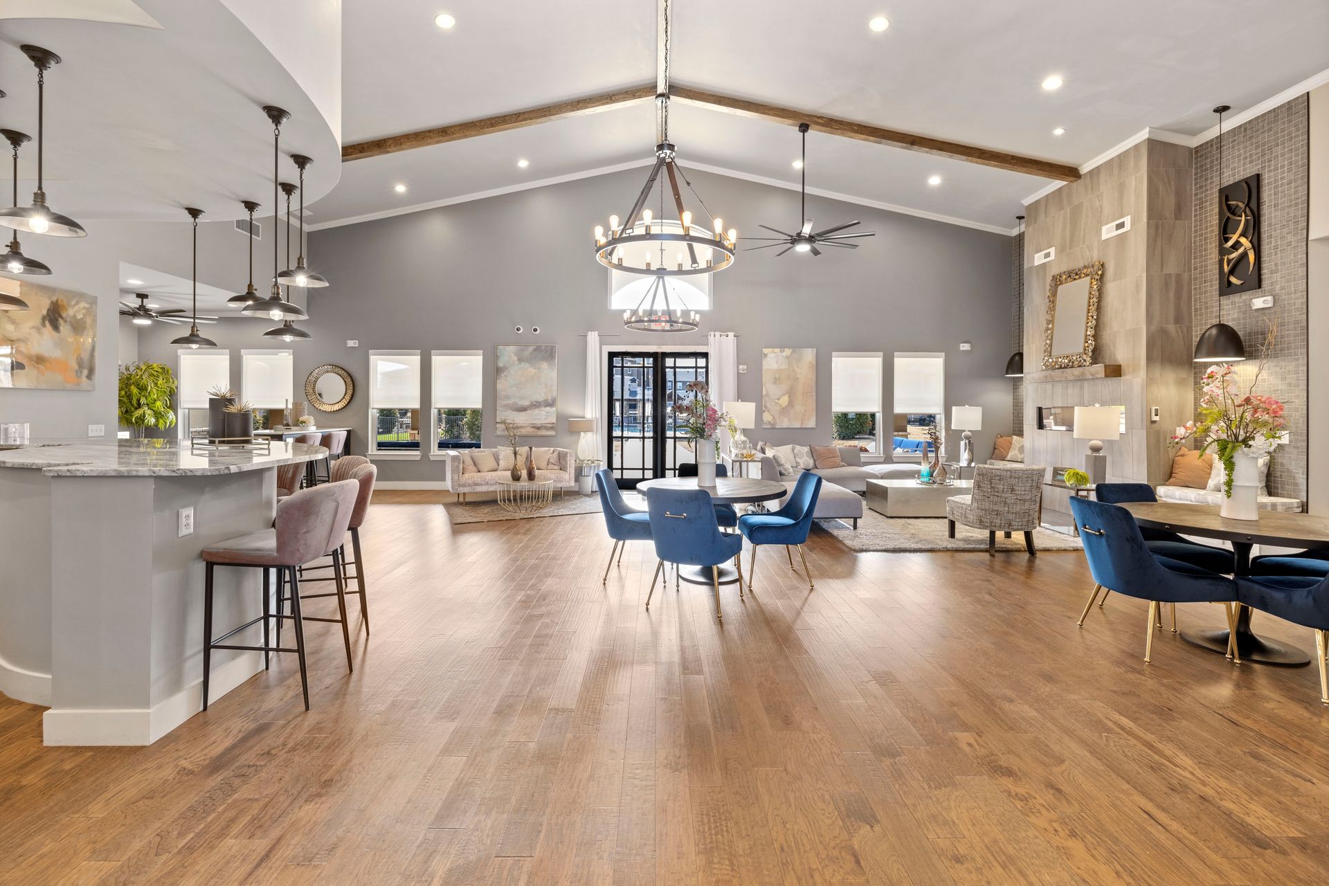 Large open room with hardwood floors, multiple seating areas, and a bar.