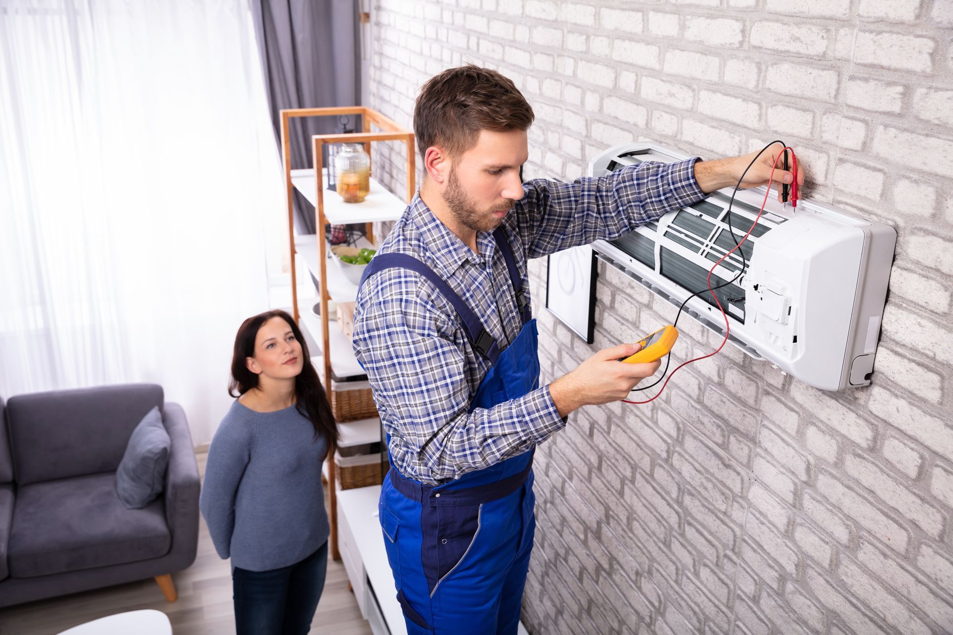 A technician carefully examines an air conditioner using a digital multimeter to diagnose and troubleshoot potential issues.