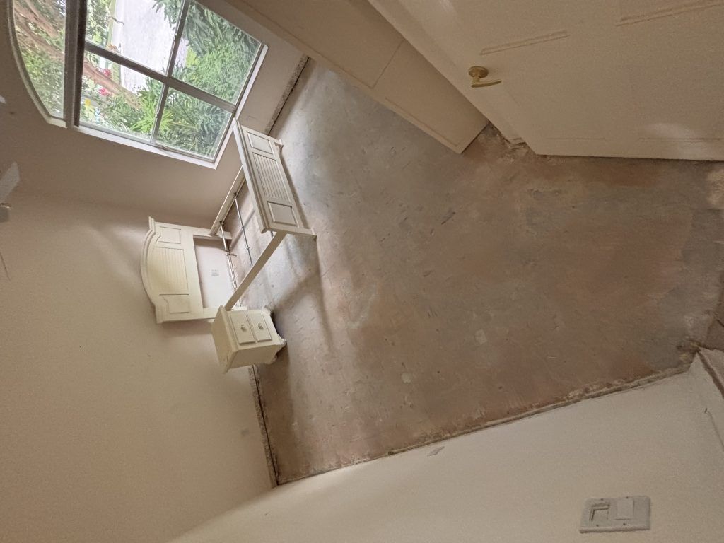 Interior room with window, off-white walls, and a light-colored floor. Furniture along one wall.