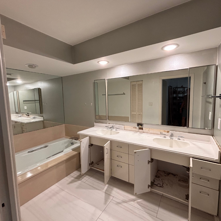 Bathroom with double sink vanity and bathtub, cabinets open, white and beige colors.