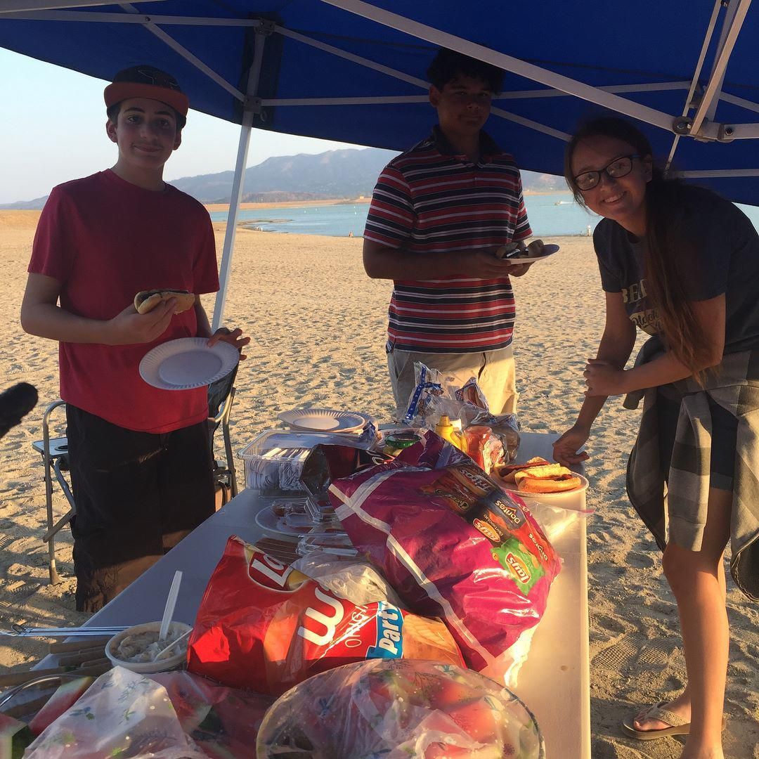 A group of people standing around a table with a bag of lays chips on it