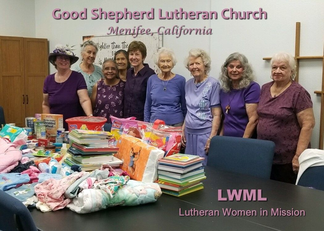 A group of women are posing for a picture in front of a table full of items.
