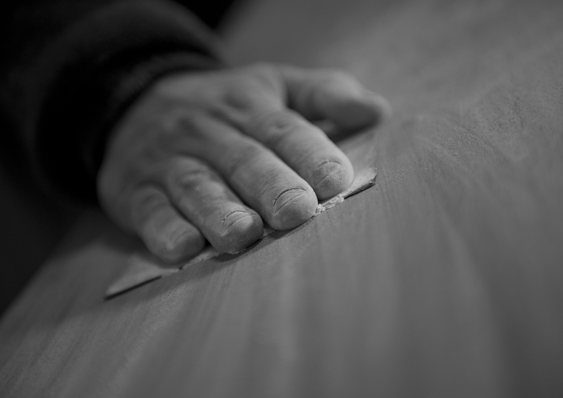 Una foto in bianco e nero di una persona che taglia un pezzo di legno.