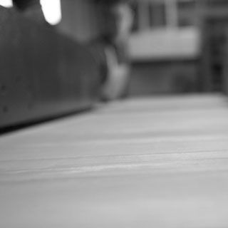 Una foto in bianco e nero di una persona che taglia un pezzo di legno.