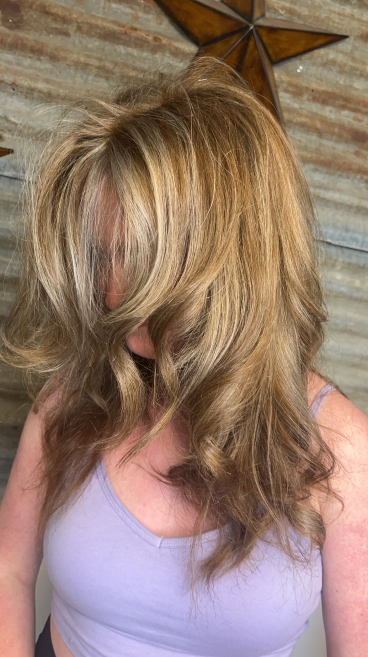 A woman in a purple tank top is covering her face with her hair.