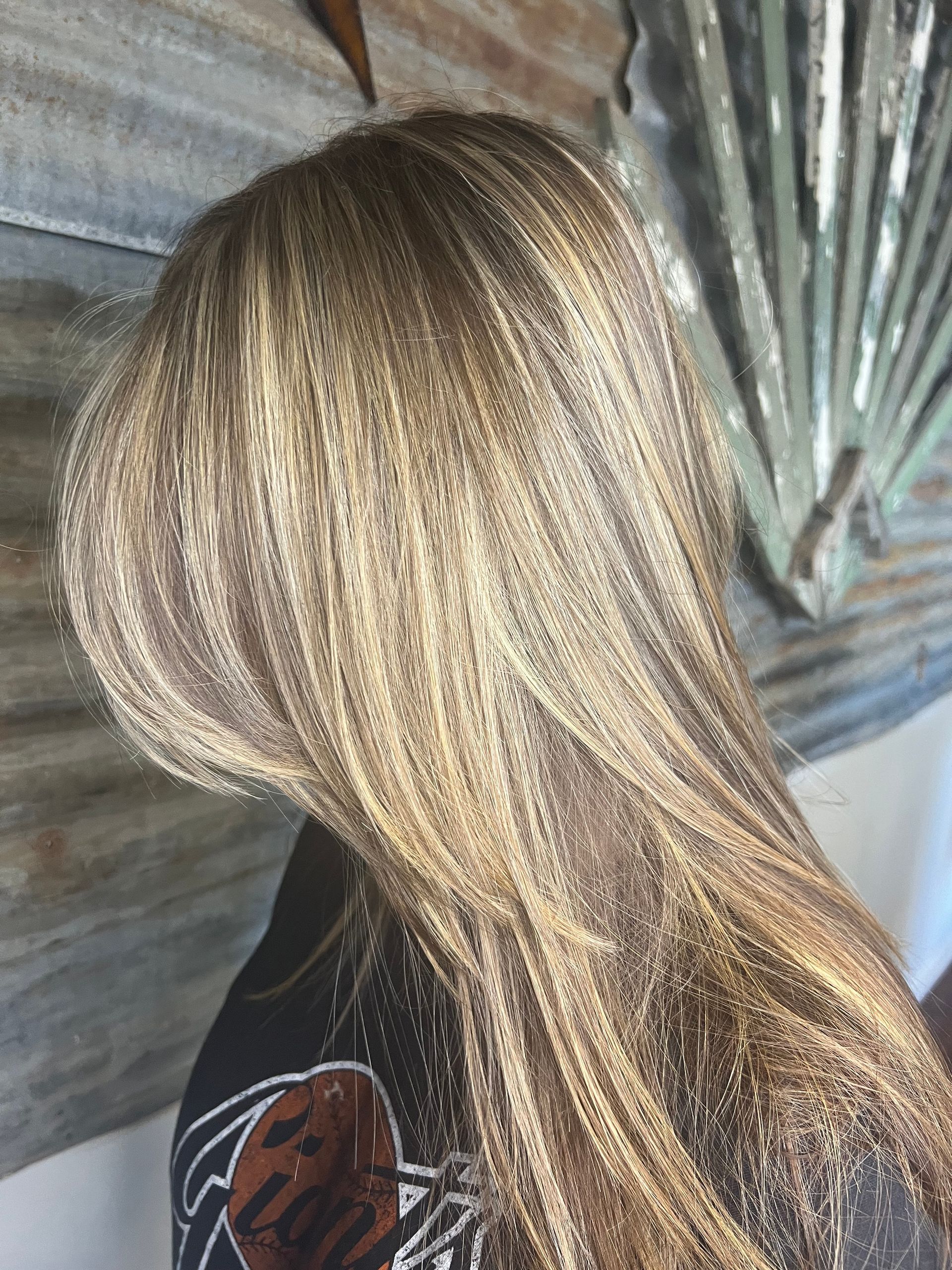 A woman with long blonde hair is standing in front of a wall.