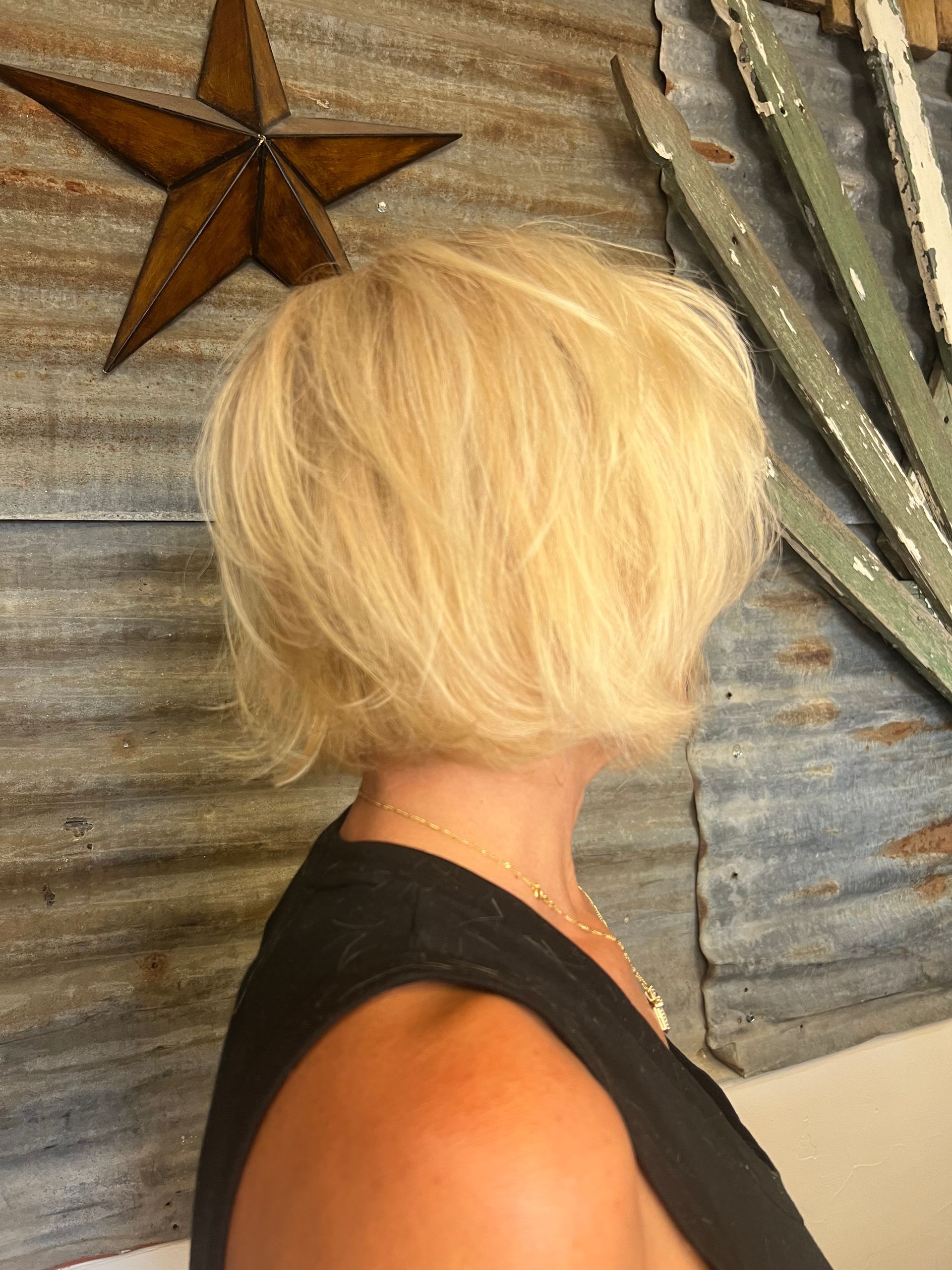 A woman with blonde hair is standing in front of a star on a wall.