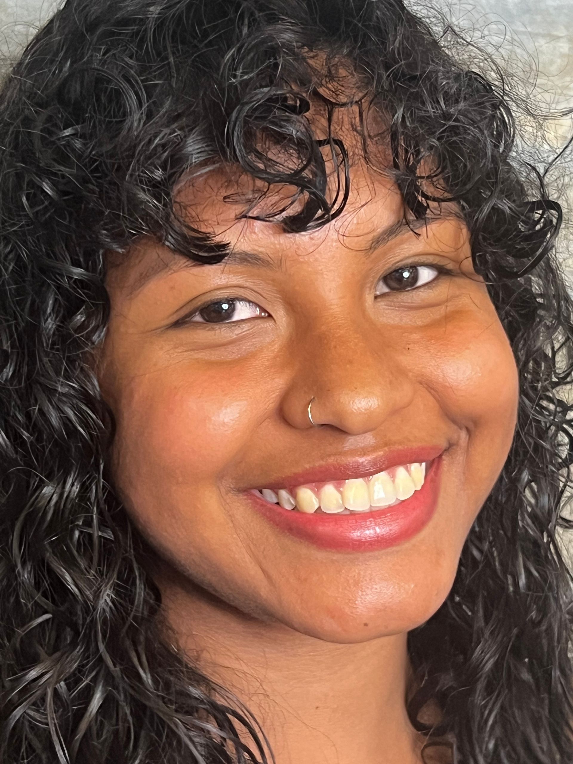 A close up of a woman 's face with curly hair smiling.