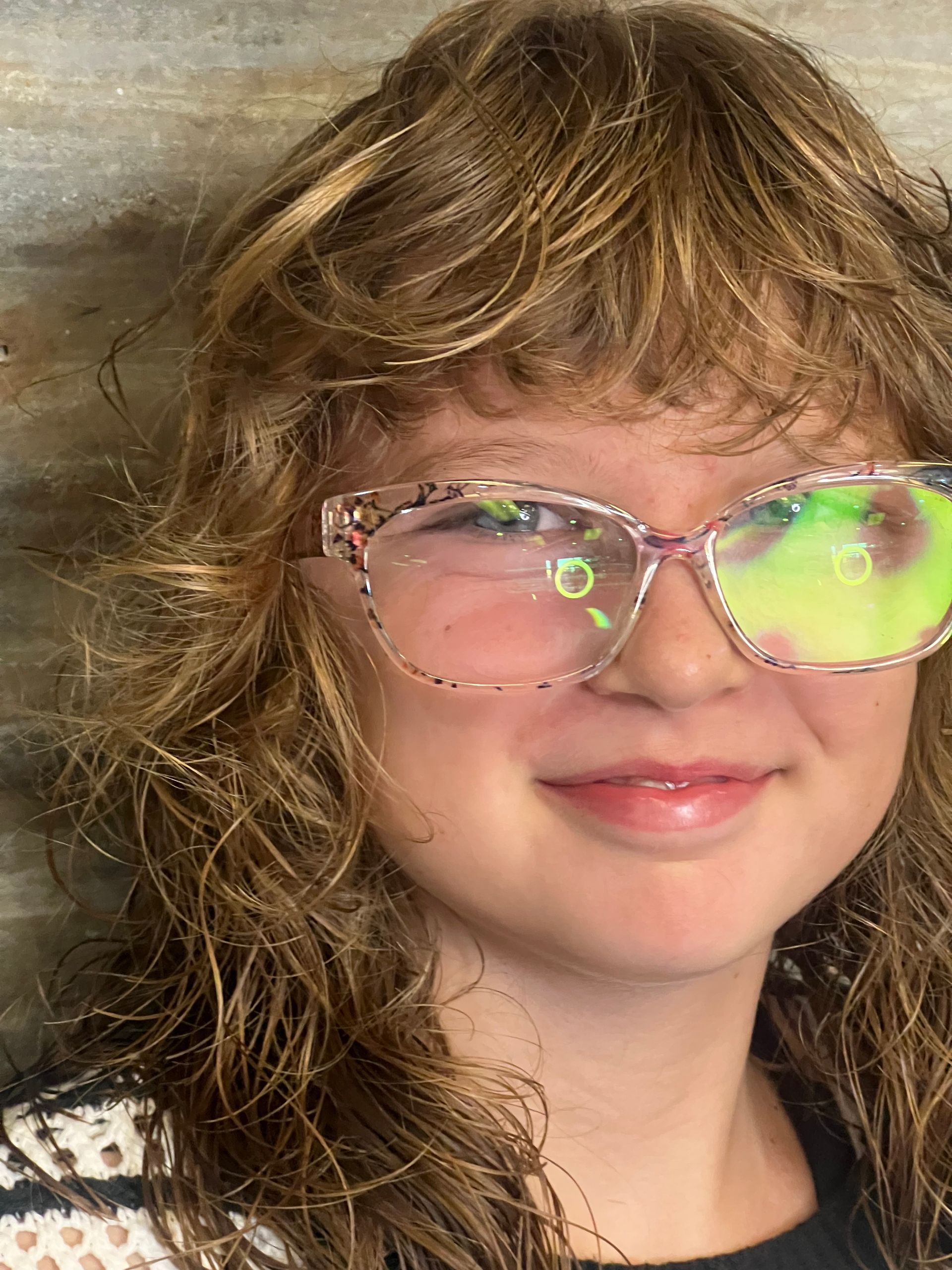 A close up of a young girl wearing glasses and smiling.