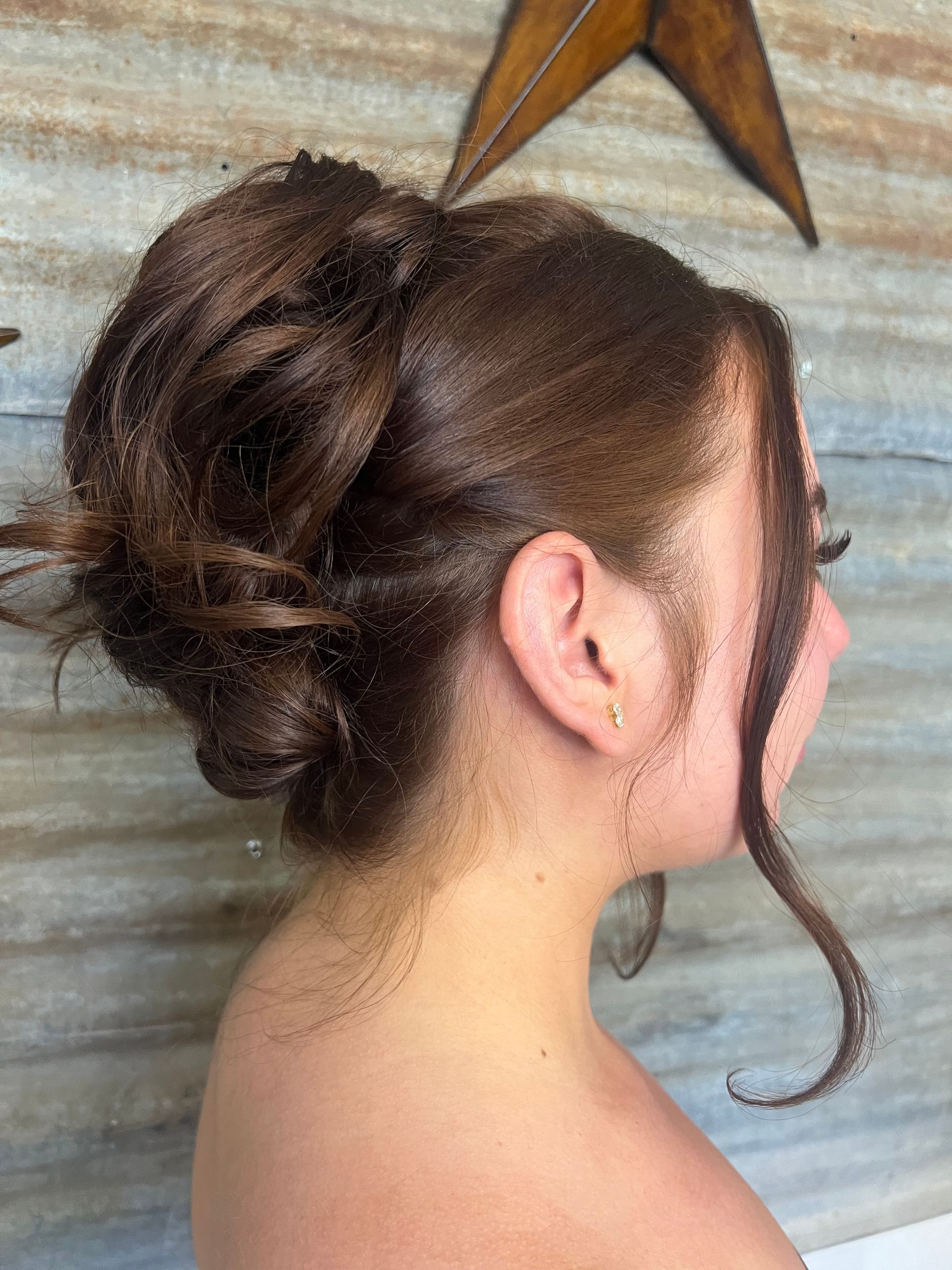 A woman is wearing her hair in a messy bun.