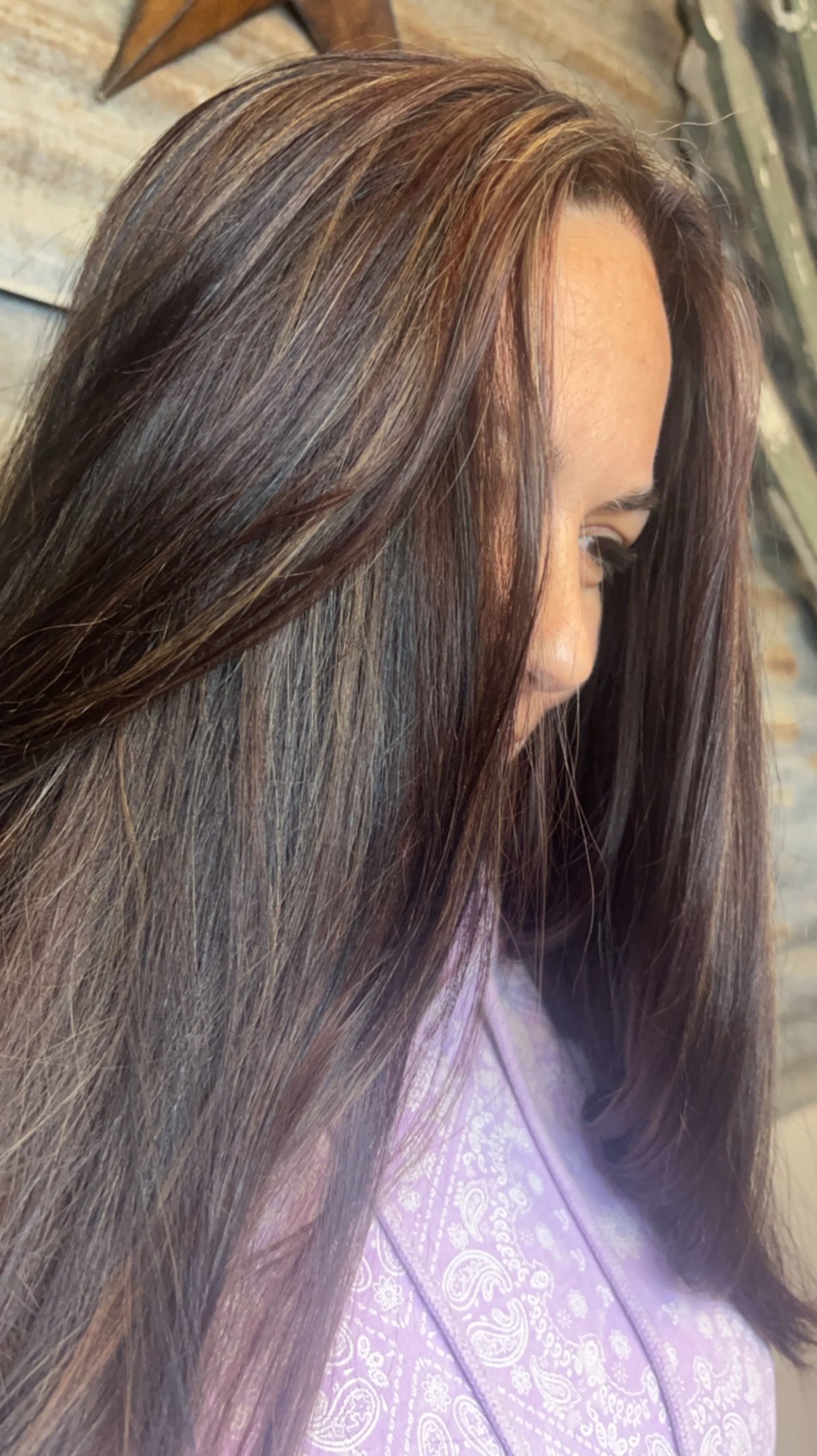 A woman with long brown hair is wearing a purple shirt.