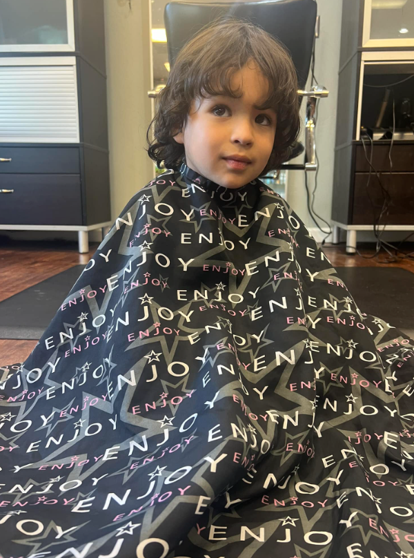 A little boy is getting his hair cut in a salon.