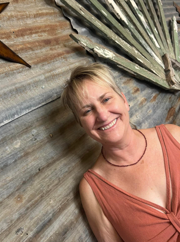 A woman in a red dress is smiling while laying on the floor.