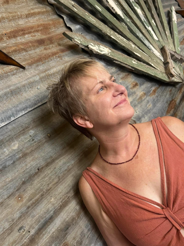 A woman in a red dress is laying on the floor next to a fan.
