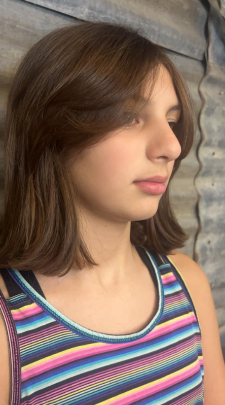 A young girl wearing a striped tank top looks to the side