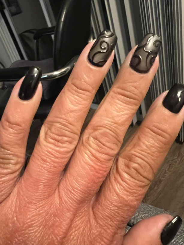A close up of a woman 's hand with black nails