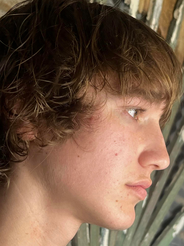 A close up of a young man 's face with curly hair.