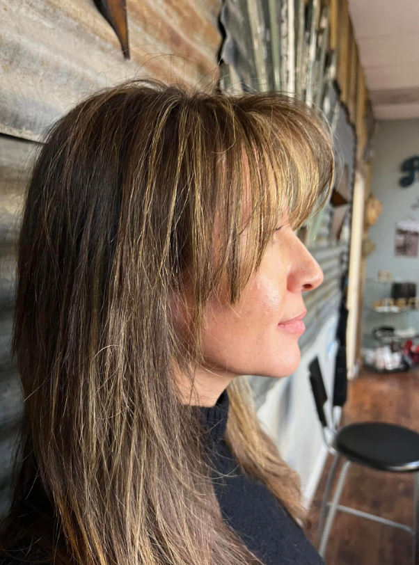 A woman with long hair and bangs is sitting in a chair in a room.