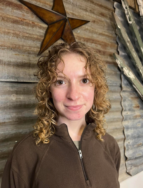 A woman with curly hair is standing in front of a star.