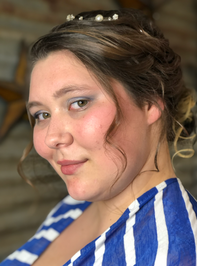 A woman wearing a blue and white striped shirt is looking at the camera.