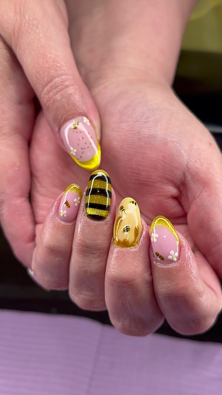 A close up of a person 's nails with a bee design on them.