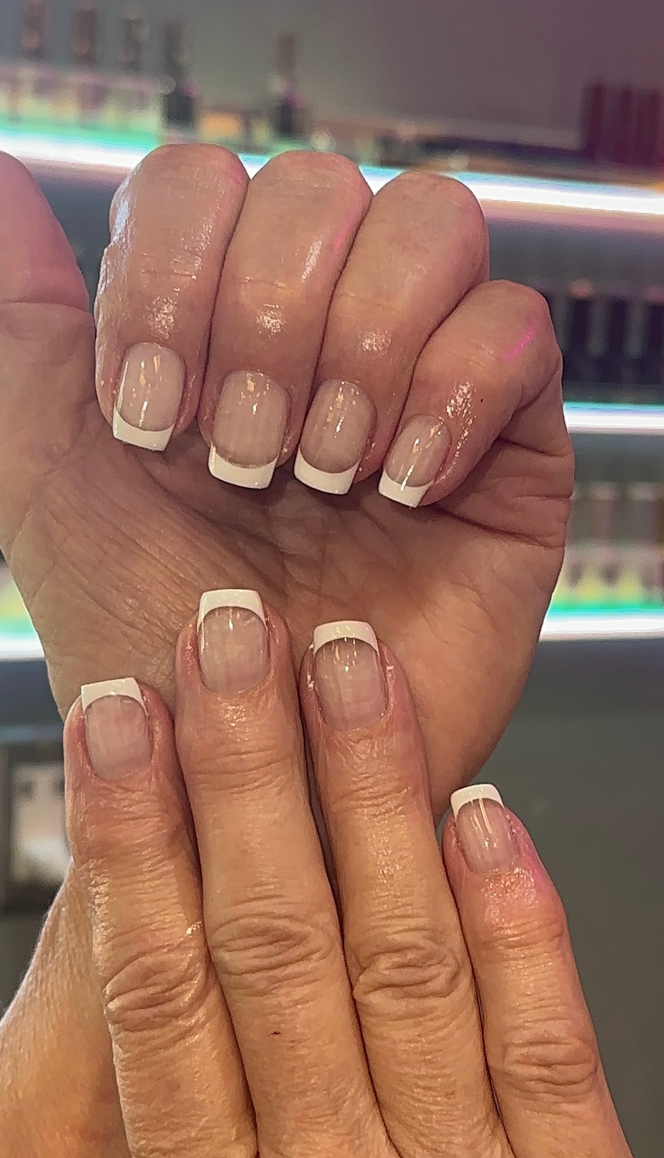 A close up of a woman 's nails with french manicure.