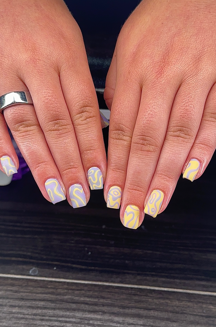 A close up of a person 's hands with yellow and purple nails.