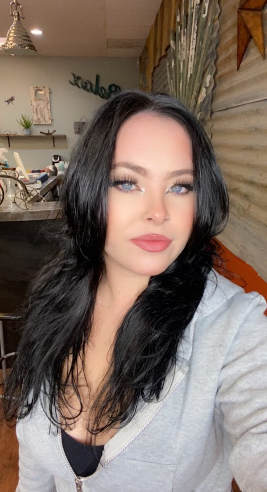 A woman with long black hair is taking a selfie in a room.