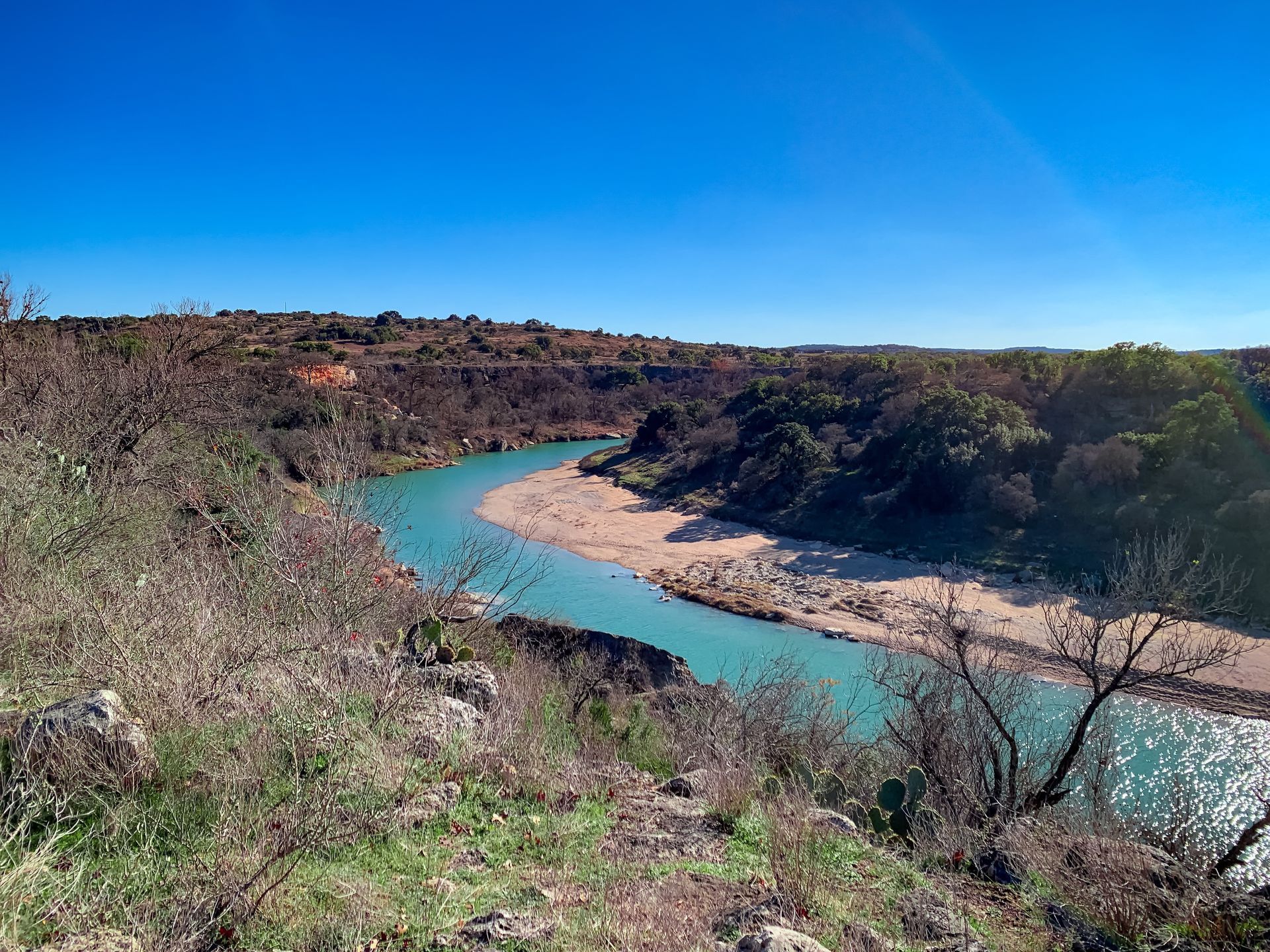 Turquoise river winding through a dry canyon under a clear blue sky