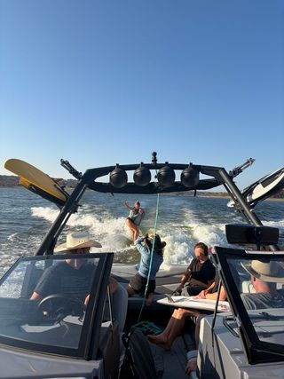 People on a motorboat fishing on open water under a clear blue sky