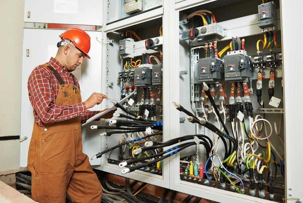 A Man in a Hard Hat is Working on an Electrical Box — Bangalow Electrical in Bangalow, NSW