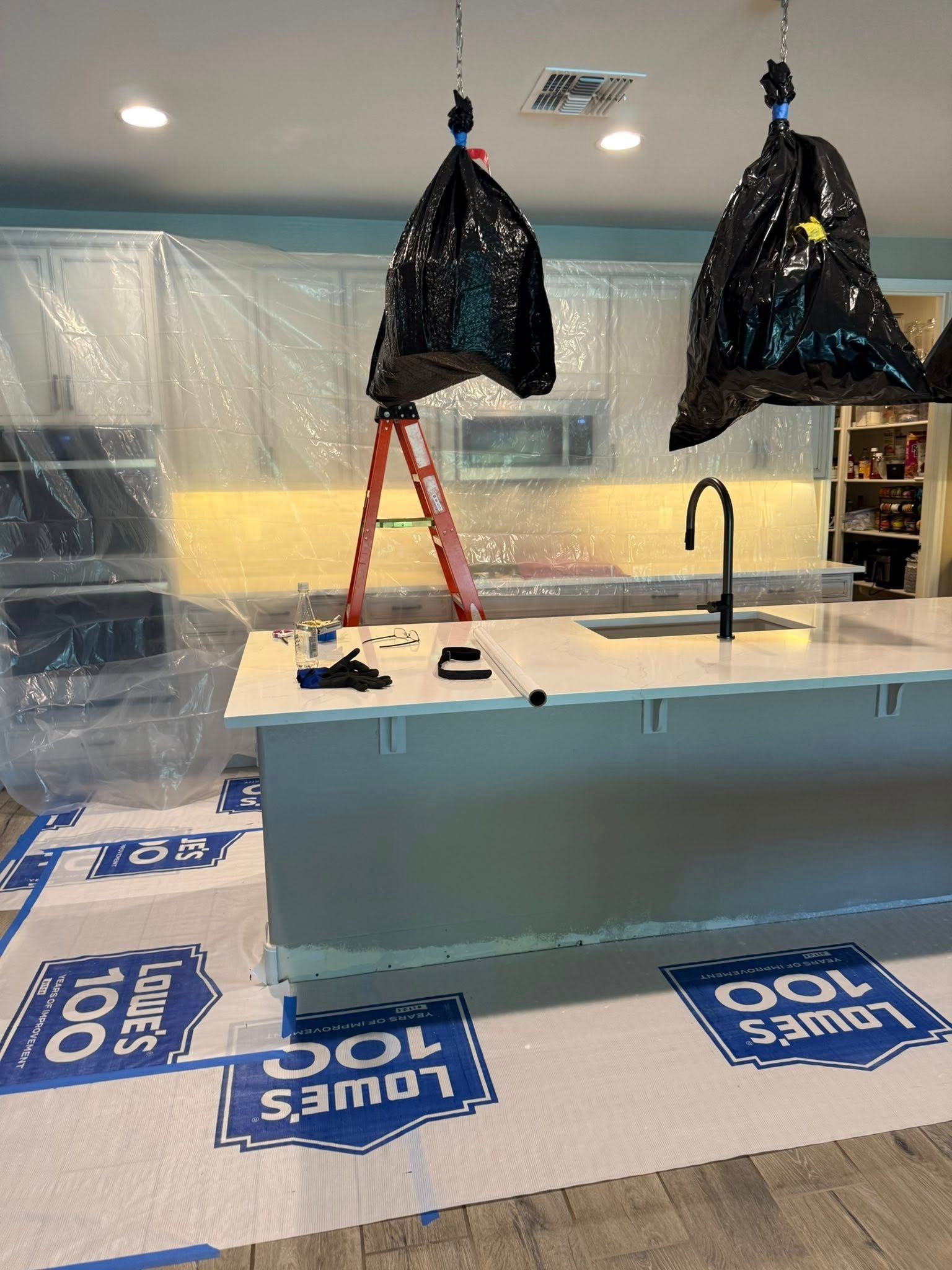 Kitchen renovation: Plastic covers cabinets, floors, and a center island. 