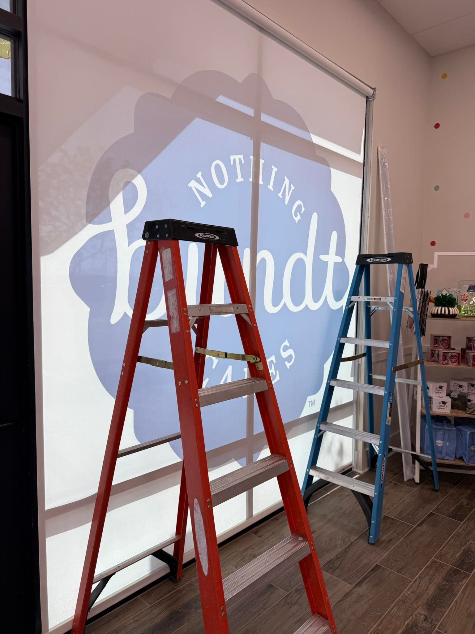 Red and blue ladders in front of a white wall with a logo.