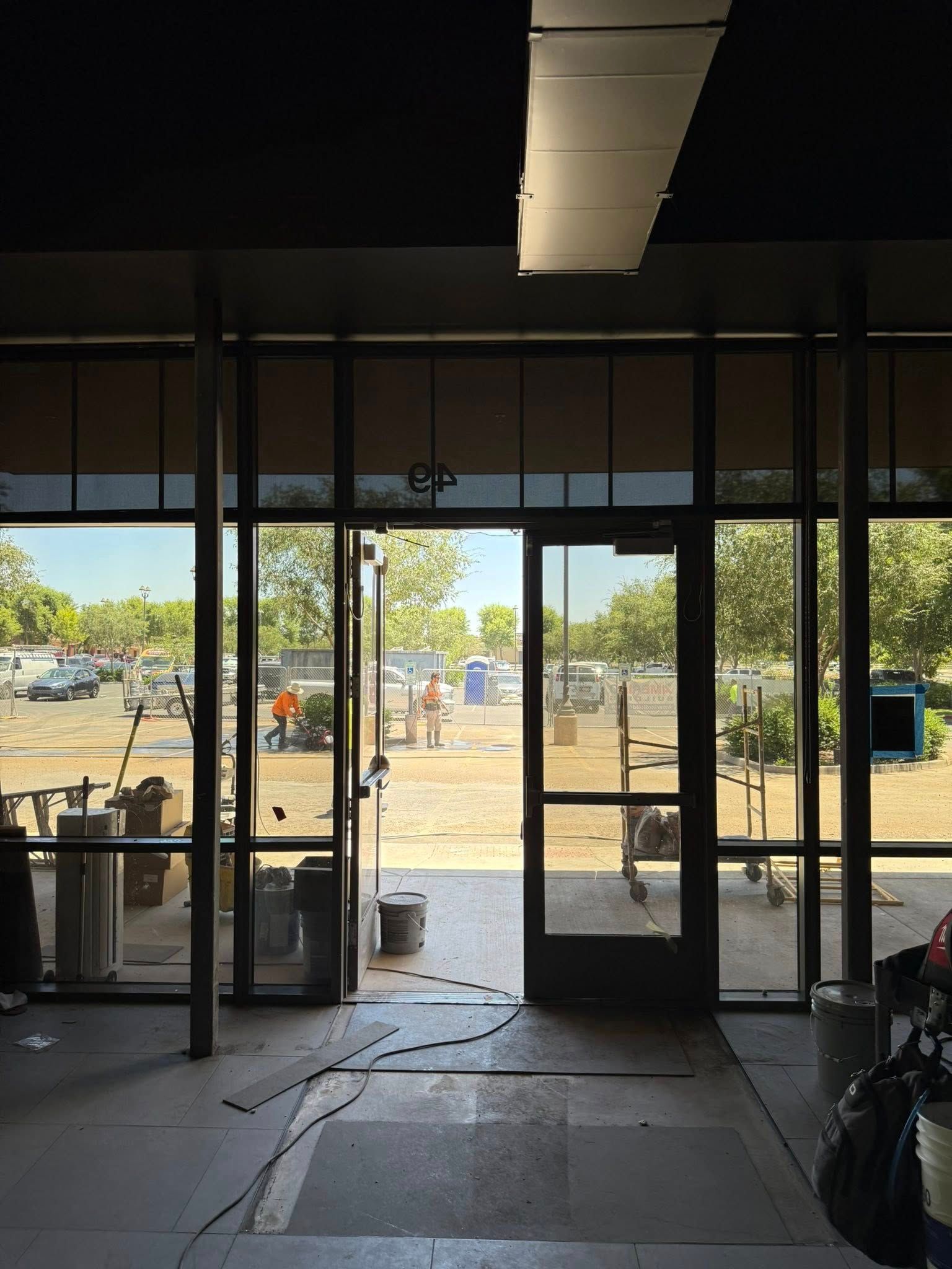 Interior view of a building with open glass doors looking out onto a construction site.