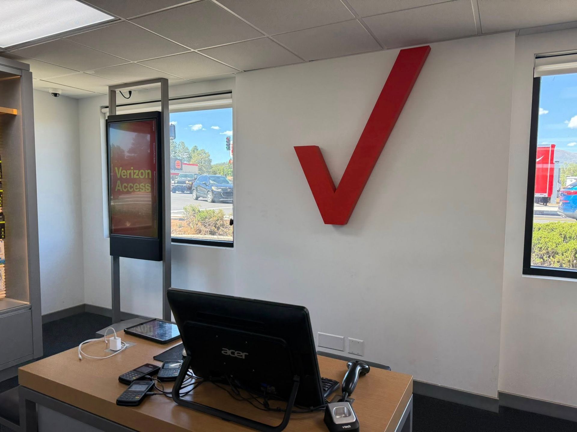 Interior of a Verizon store with large red check mark on white wall, desk, and windows.