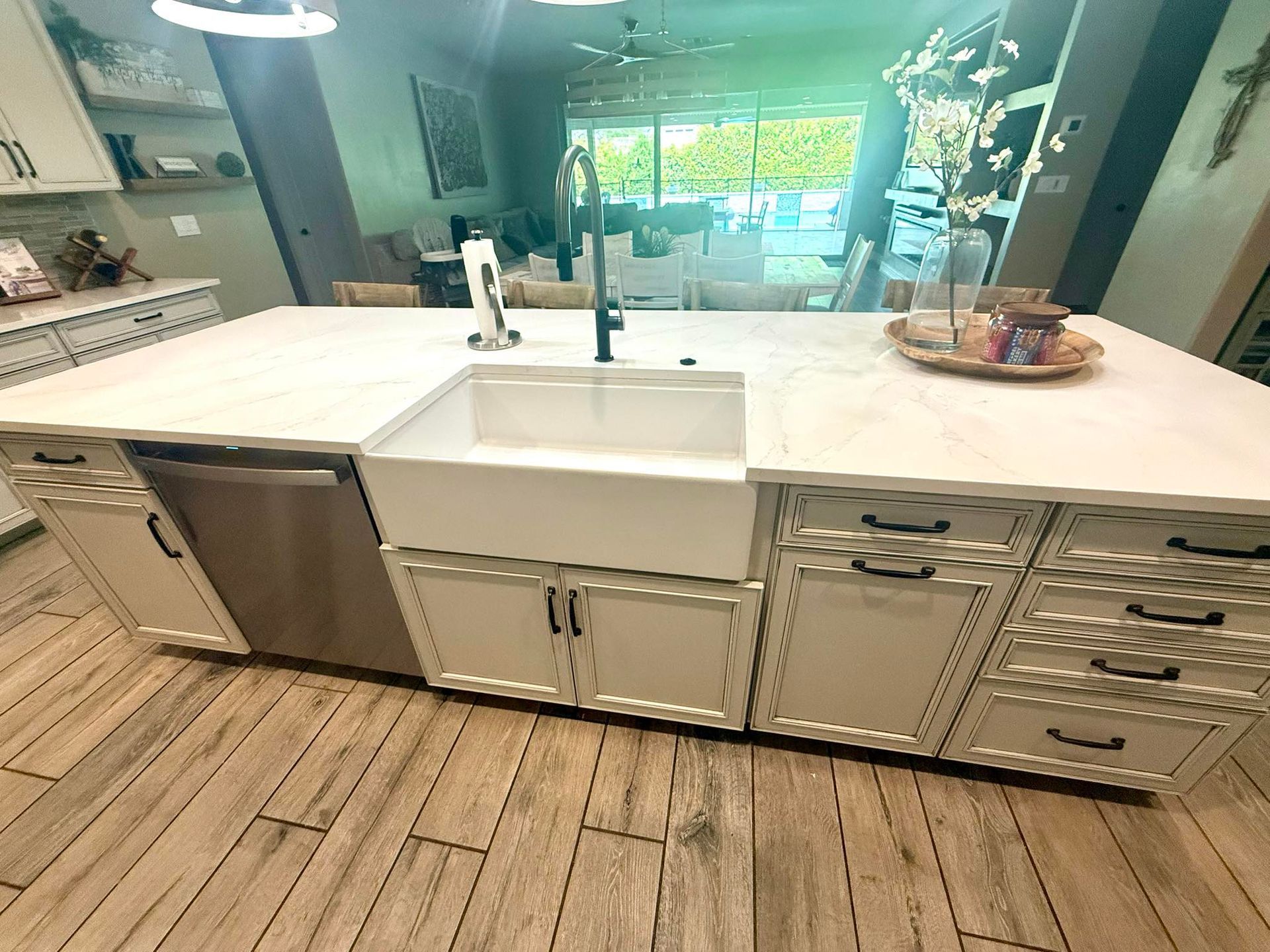 Kitchen island with white cabinets, stainless steel dishwasher, farmhouse sink, and black faucet.