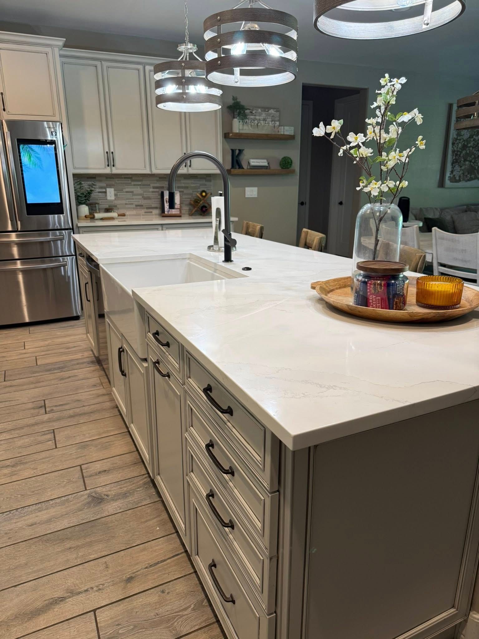 Kitchen with a large island, cabinets, countertops, and pendant lights.