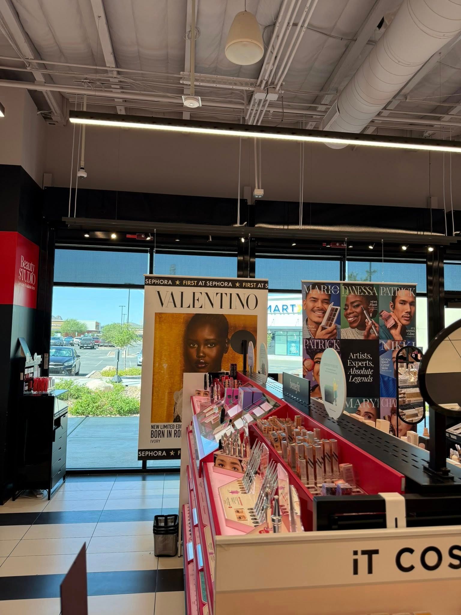 Inside a brightly lit cosmetics store, product displays are visible with a Valentino advertisement in the background.
